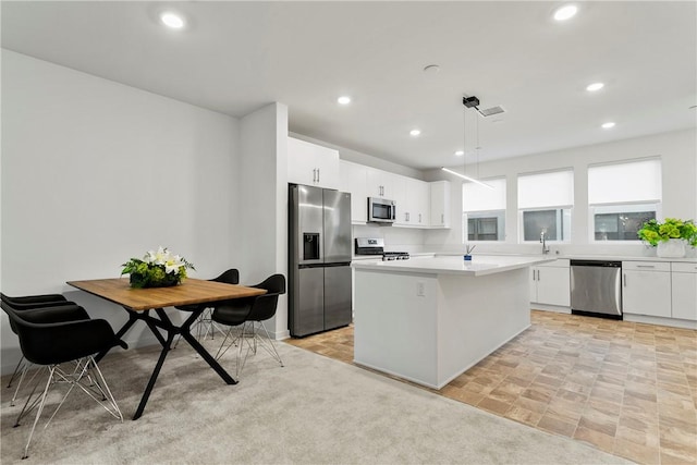 kitchen with white cabinets, decorative light fixtures, light carpet, a kitchen island, and appliances with stainless steel finishes