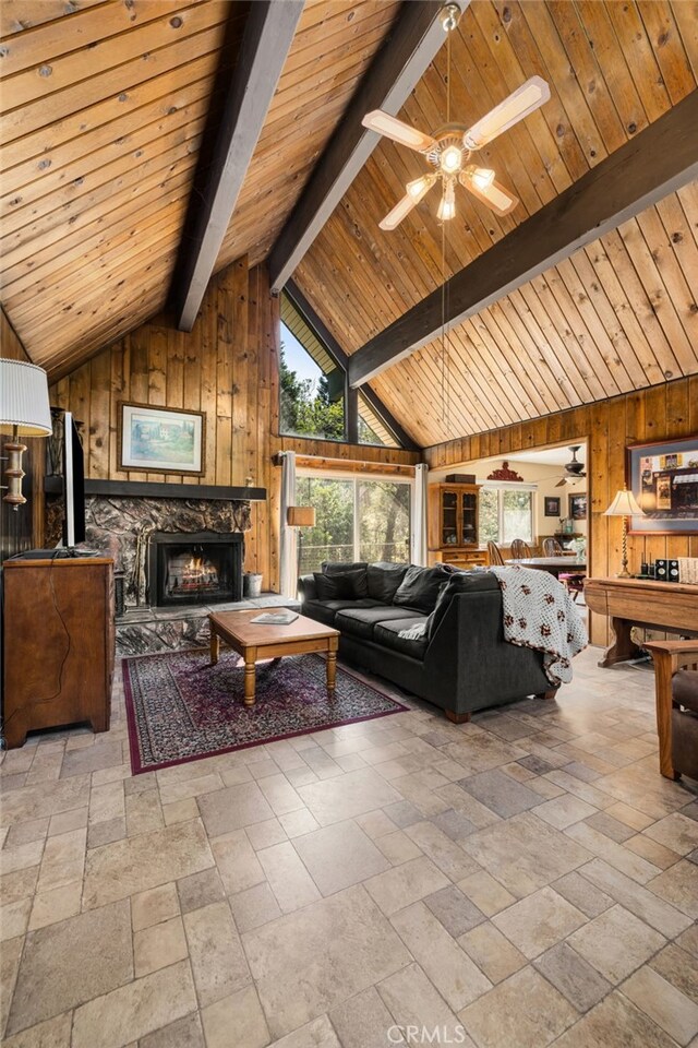 living area featuring wooden walls, stone tile floors, and lofted ceiling with beams