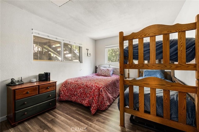 bedroom with dark wood-type flooring and a textured wall