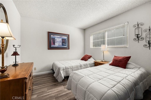 bedroom featuring a textured ceiling, baseboards, and wood finished floors