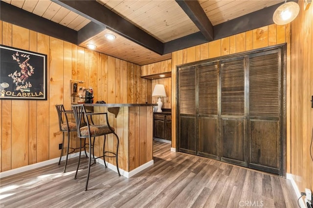 bar with wooden walls, a bar, beamed ceiling, wooden ceiling, and wood finished floors
