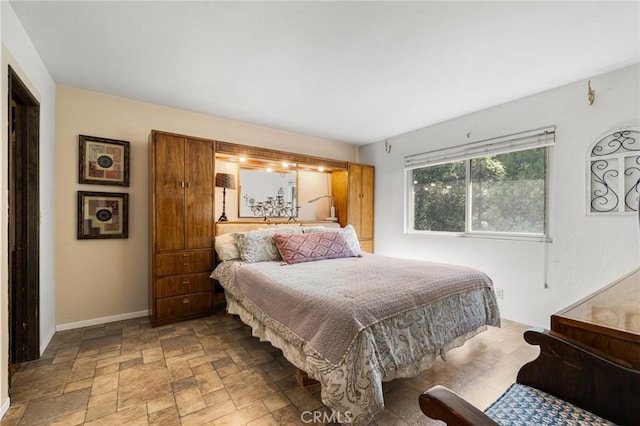 bedroom with baseboards and stone finish flooring