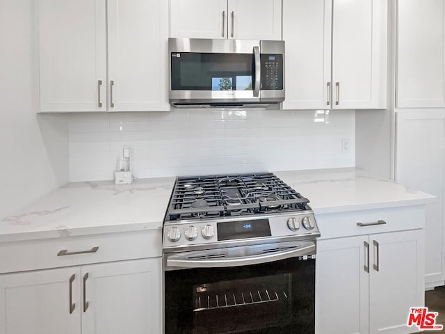 kitchen featuring white cabinets, appliances with stainless steel finishes, and light stone countertops