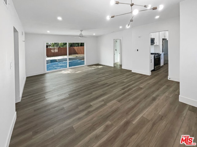 unfurnished living room with ceiling fan with notable chandelier and dark hardwood / wood-style floors