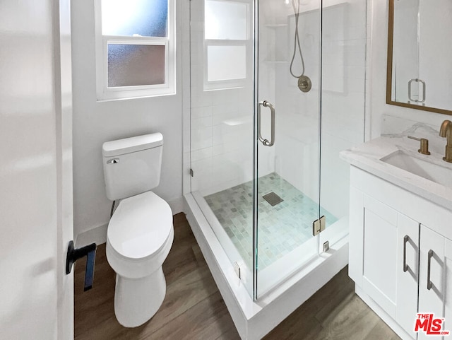 bathroom featuring vanity, wood-type flooring, an enclosed shower, and toilet