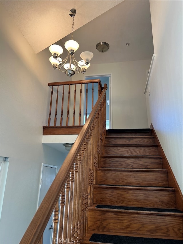 stairs featuring a chandelier and vaulted ceiling