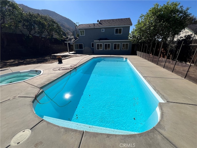 view of pool with an in ground hot tub, a mountain view, and a patio area