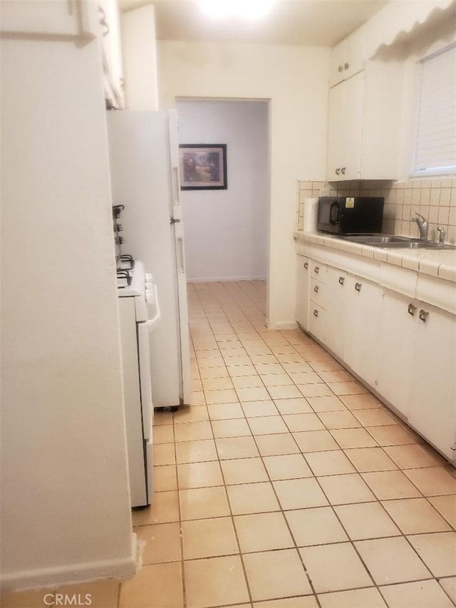 kitchen featuring tasteful backsplash, white cabinetry, sink, white range, and tile counters