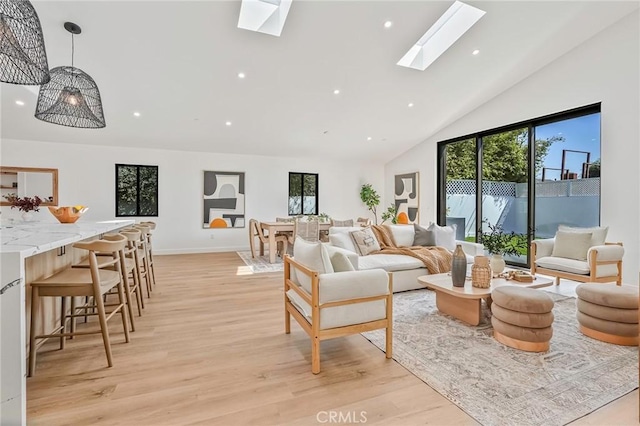 living room featuring baseboards, recessed lighting, a skylight, light wood-style floors, and high vaulted ceiling