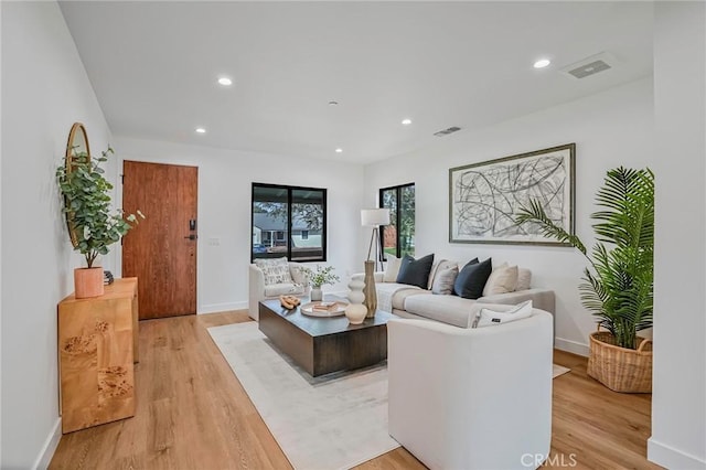 living area with recessed lighting, visible vents, light wood-style flooring, and baseboards