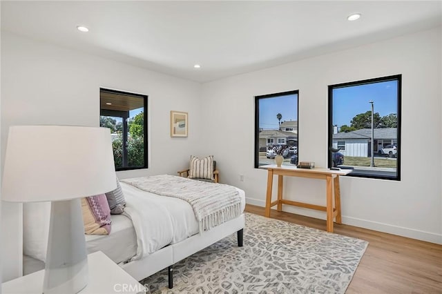 bedroom with recessed lighting, multiple windows, baseboards, and wood finished floors