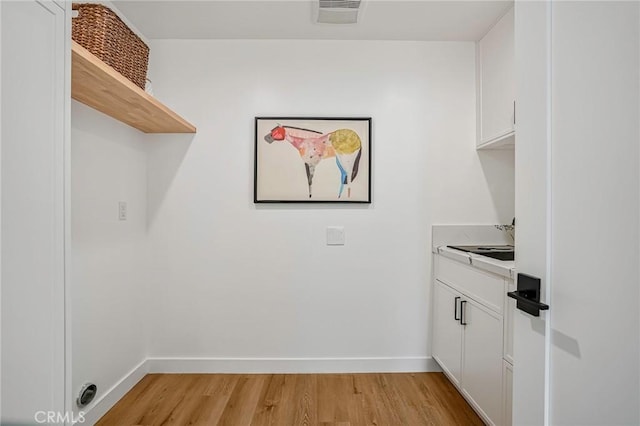 laundry room with light wood-style floors, visible vents, and baseboards