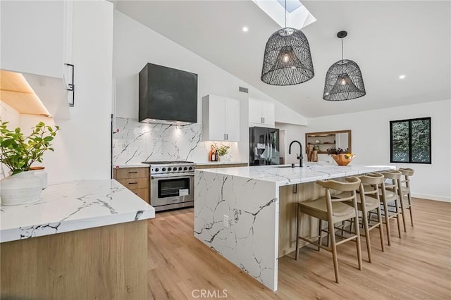 kitchen featuring light wood-style flooring, a sink, high end stainless steel range, modern cabinets, and black fridge