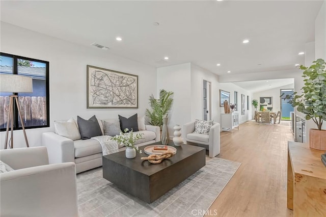 living room with vaulted ceiling, light wood-style flooring, recessed lighting, and visible vents