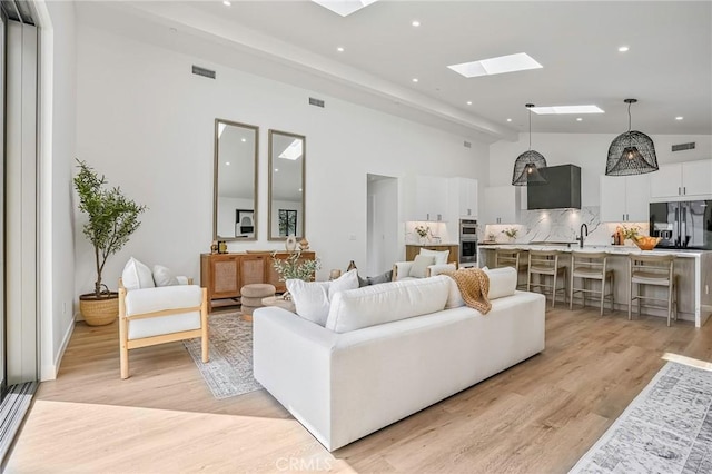 living area featuring light wood-type flooring, visible vents, and a skylight