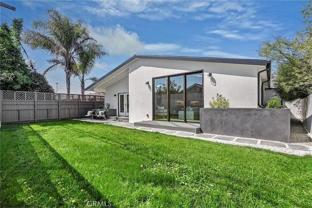 back of property with stucco siding, a patio, a yard, and fence