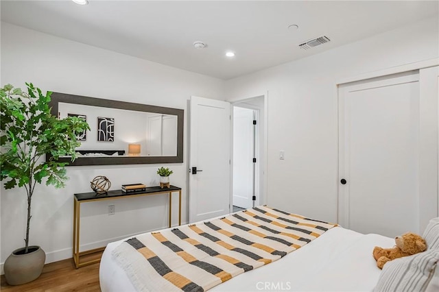 bedroom featuring recessed lighting, wood finished floors, visible vents, and a closet