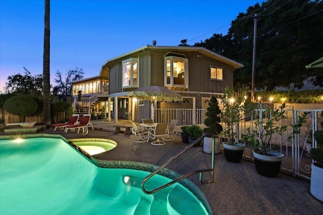 back house at dusk featuring a patio and a fenced in pool