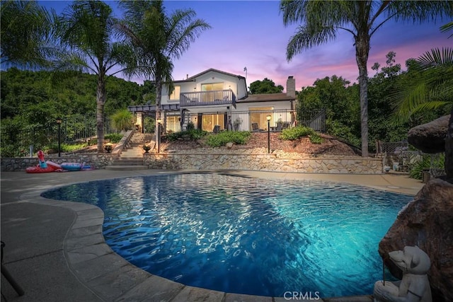 pool at dusk with a patio area