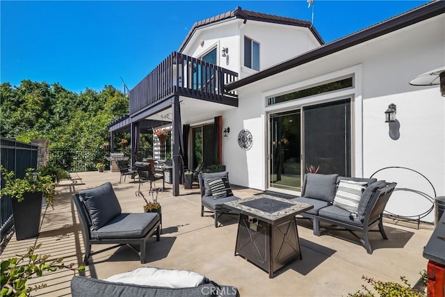 view of patio featuring a balcony and an outdoor living space with a fire pit