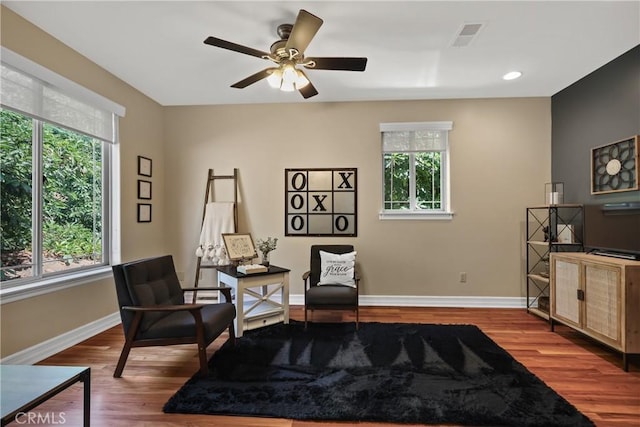 living area featuring wood-type flooring, a healthy amount of sunlight, and ceiling fan