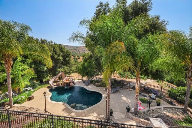 view of swimming pool with a water slide and a patio area