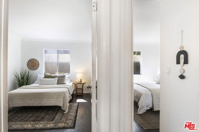 bedroom with crown molding and dark hardwood / wood-style floors