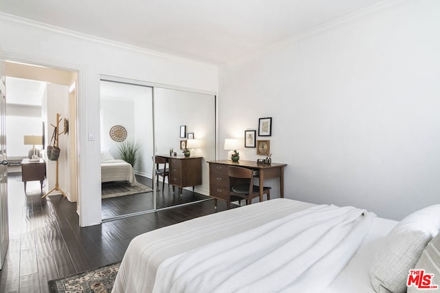 bedroom with crown molding, a closet, and dark wood-type flooring