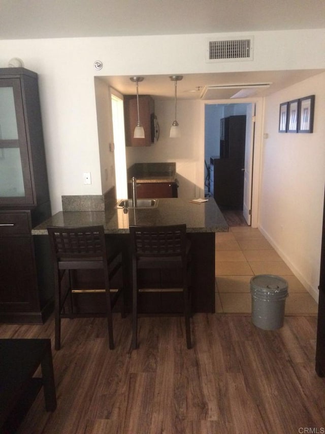 kitchen with hardwood / wood-style flooring, sink, kitchen peninsula, and hanging light fixtures