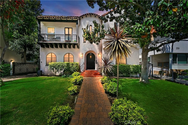 mediterranean / spanish home with a balcony and a lawn