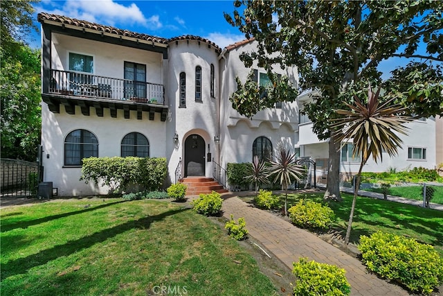 mediterranean / spanish-style house with a front yard and a balcony