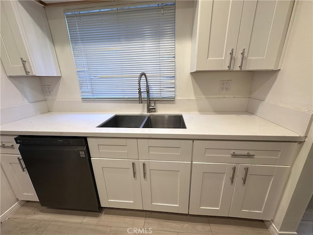 kitchen with white cabinetry, black dishwasher, and sink