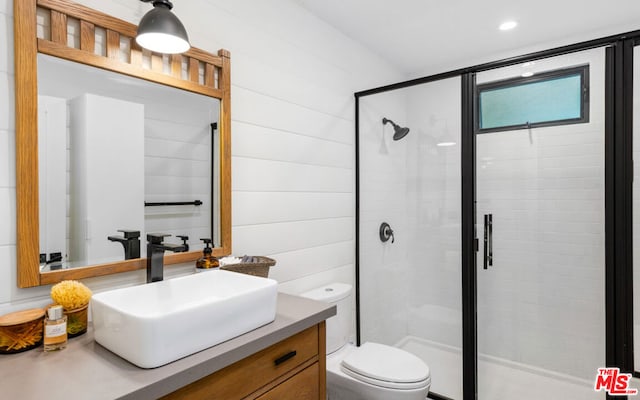 bathroom with vanity, toilet, an enclosed shower, and wooden walls