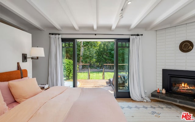 bedroom featuring hardwood / wood-style floors, beam ceiling, a fireplace, and access to outside