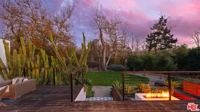 deck at dusk featuring a yard and an outdoor fire pit