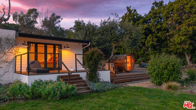 back house at dusk featuring a yard and an outbuilding