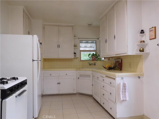 kitchen with tasteful backsplash, white cabinetry, light tile patterned floors, and white stove