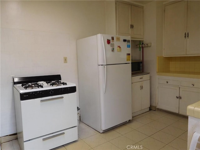 kitchen featuring white cabinets, light tile patterned flooring, and white appliances