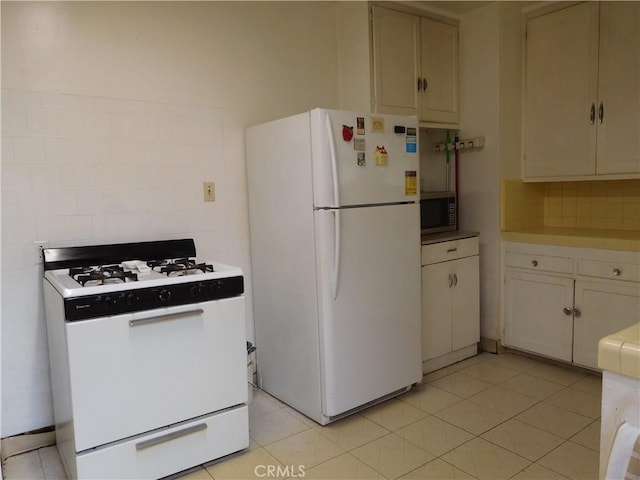 kitchen with white cabinets, light tile patterned floors, and white appliances