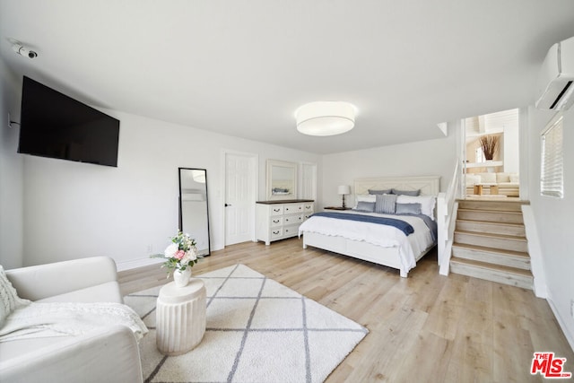 bedroom featuring a wall mounted AC and light wood-type flooring