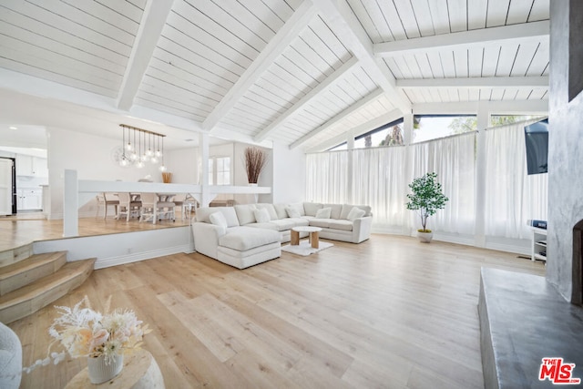 unfurnished living room with an inviting chandelier, light hardwood / wood-style floors, and vaulted ceiling with beams