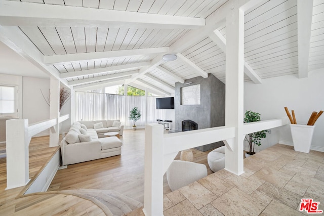 living room featuring vaulted ceiling with beams, light hardwood / wood-style floors, and a large fireplace