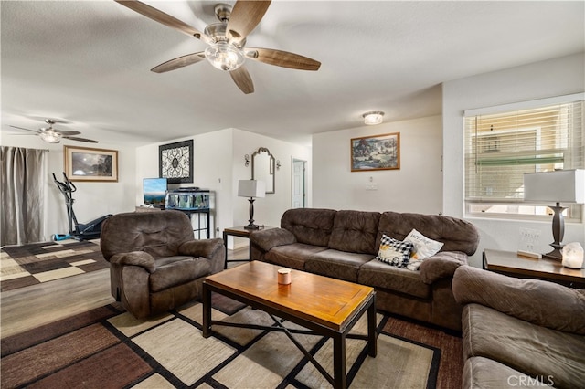 living room with a textured ceiling, light wood-type flooring, and ceiling fan