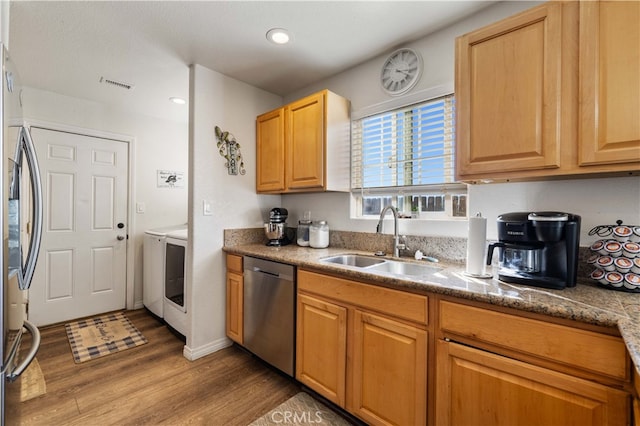 kitchen featuring washer / dryer, light brown cabinets, hardwood / wood-style flooring, stainless steel appliances, and sink