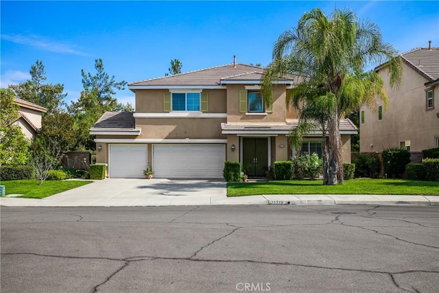 view of front of home with an attached garage, a front lawn, concrete driveway, and stucco siding