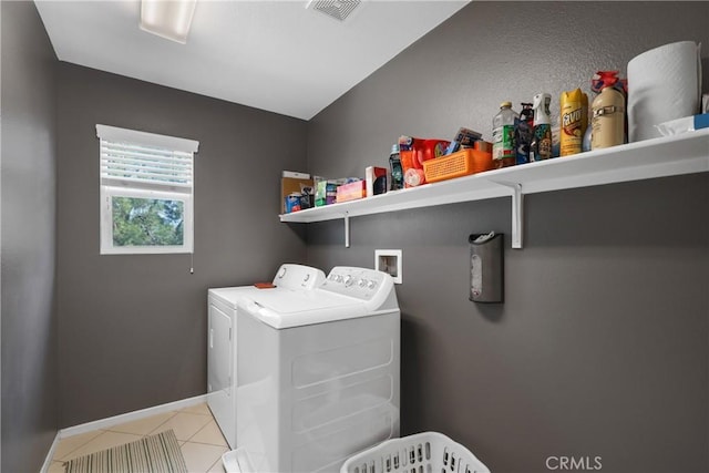 clothes washing area with laundry area, light tile patterned floors, baseboards, visible vents, and washer and dryer