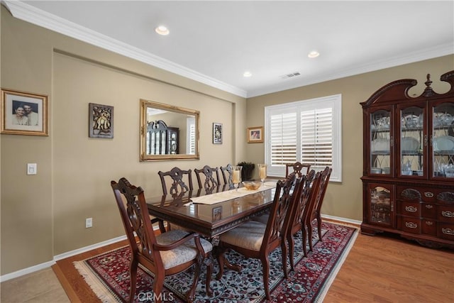 dining space featuring light wood finished floors, baseboards, visible vents, and ornamental molding