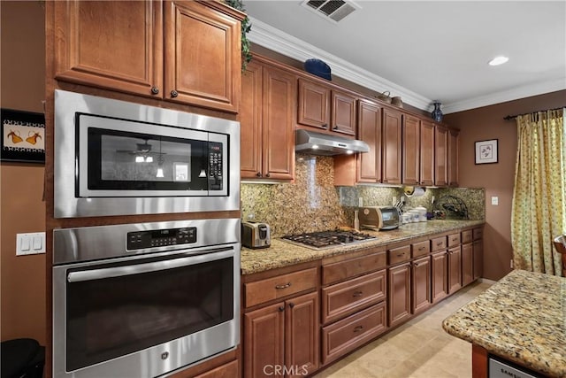 kitchen with visible vents, decorative backsplash, appliances with stainless steel finishes, light stone counters, and under cabinet range hood