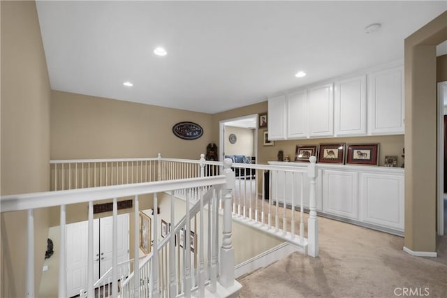 hallway featuring light carpet, recessed lighting, and an upstairs landing