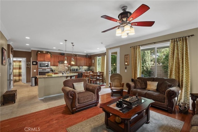 living area featuring light tile patterned floors, ceiling fan, ornamental molding, and recessed lighting